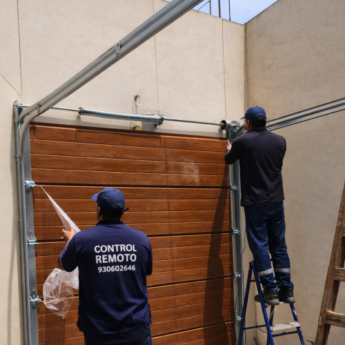 Técnicos de Control Remoto instalando puerta seccional de garaje con guías y estructura metálica
